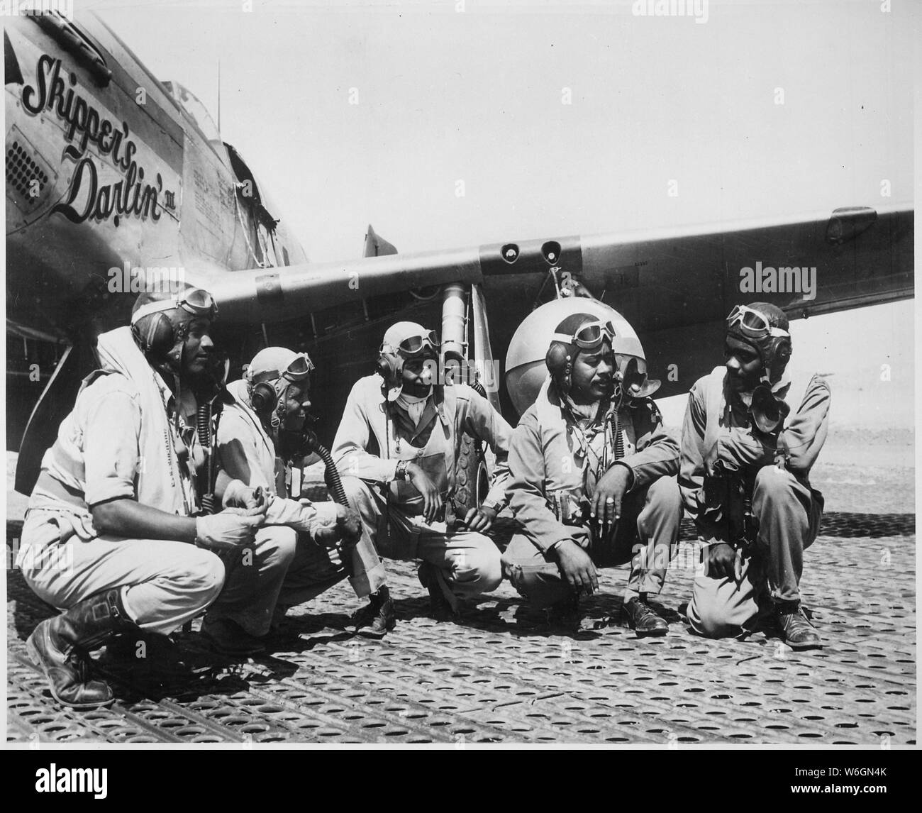 Fliers of a P-51 Mustang Group of the 15th Air Force in Italy `shoot the breeze' in the shadow of one of the Mustangs they fly., ca. 08/1944; Scope and content:  Left to right: Lt. Dempsey W. Morgan, Jr.; Lt. Carroll S. Woods; Lt. Robert H. Nelson, Jr.; Capt. Andrew D. Turner; and Lt. Clarence P. Lester. Stock Photo